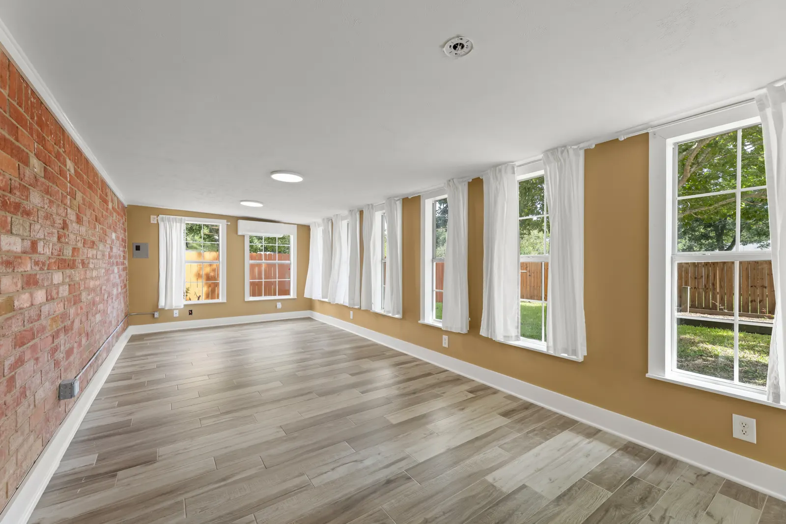 Enlarged family room with exposed brick wall and a long row of windows