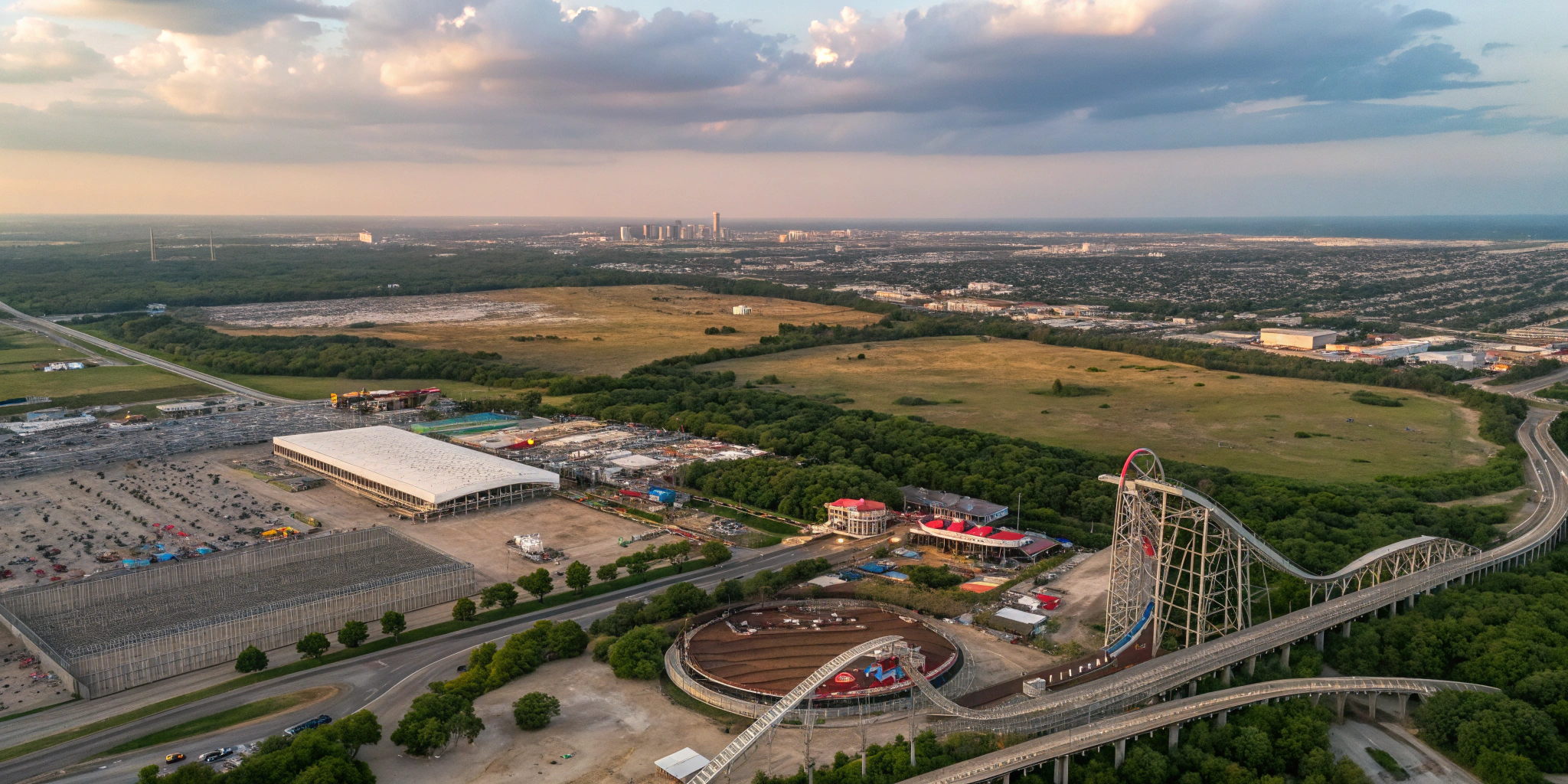 A dramatic aerial image of a sprawling Texas landscape with a winding rollercoaster seamlessly integrated into the scenery, showcasing a mix of bustling urban development and vast undeveloped land.